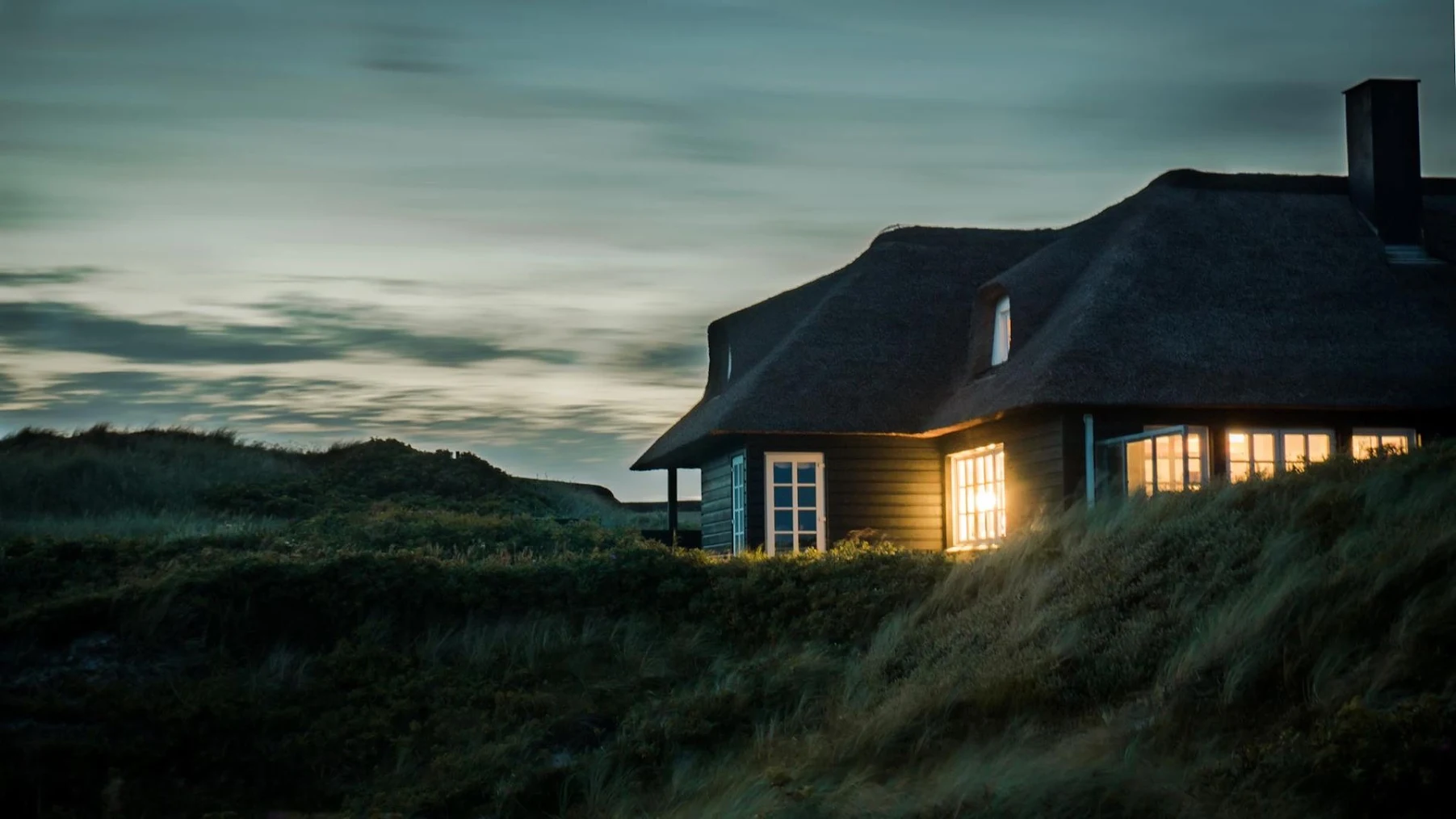 a home atop a hill, illuminated by light in the evening.